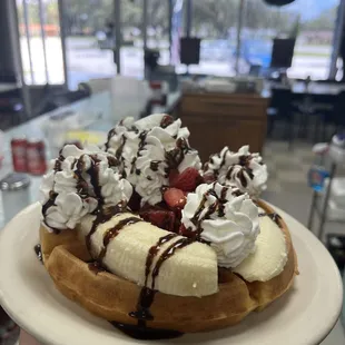 banana split waffle, topped with banana, strawberries, and chocolate syrup