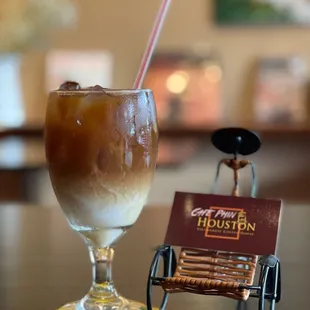 a glass of iced coffee and a card on a table