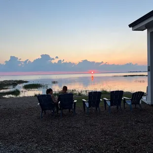 two people sitting in chairs facing the water
