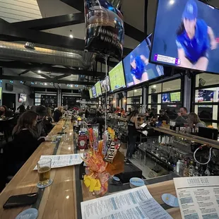 people sitting at a bar watching televisions