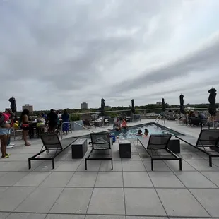 a pool and lounge chairs on a rooftop