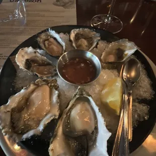 a plate of oysters with a side of dipping sauce
