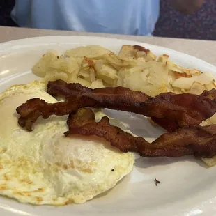 Eggs over easy, bacon strips, and fried tators.