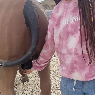 a girl standing next to a statue of a cow