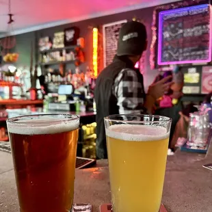 two glasses of beer on a bar