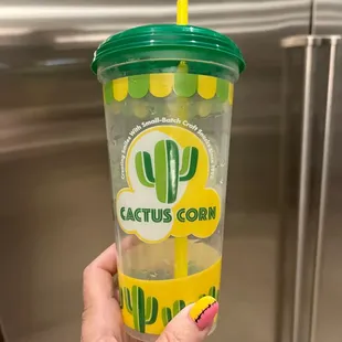 a hand holding a cup of cactus corn