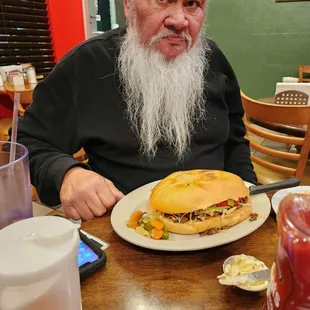 a man sitting at a table with a sandwich