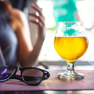 a glass of beer and sunglasses on a table