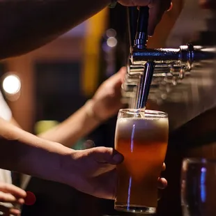 a person filling a glass of beer