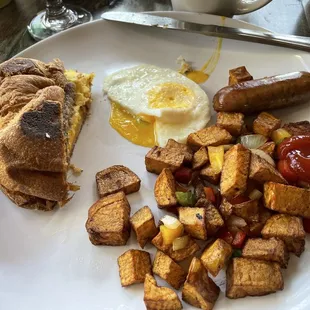 1/2 of a breakfast sandwich and single egg and sausage with country potatoes