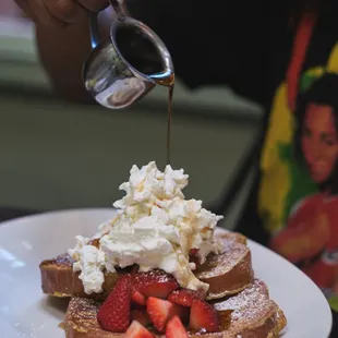 a plate of french toast with whipped cream and strawberries