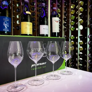 three wine glasses in front of a wine rack