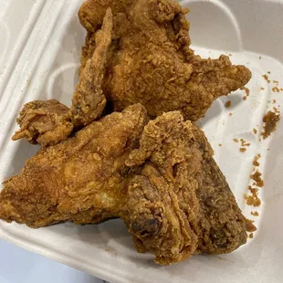 two pieces of fried chicken in a styrofoam container