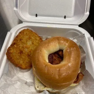 Breakfast sandwich on a bagel with a hash brown on the side