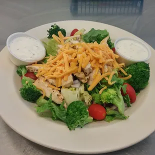 a plate of salad with chicken, broccoli and cheese