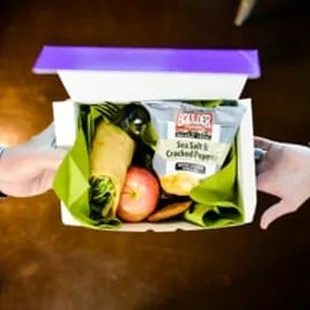 two people holding a box of fruit and vegetables