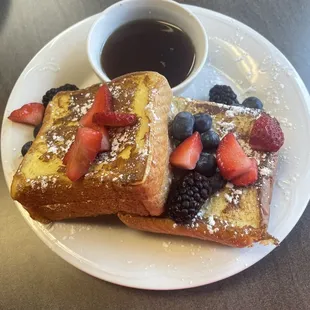 a plate of french toast with berries and powdered sugar