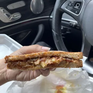 a hand holding a half eaten sandwich