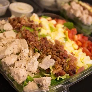 a salad with chicken, lettuce, tomatoes, and bacon