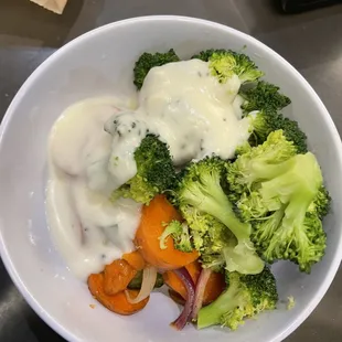 a bowl of broccoli, carrots, onions, and dressing