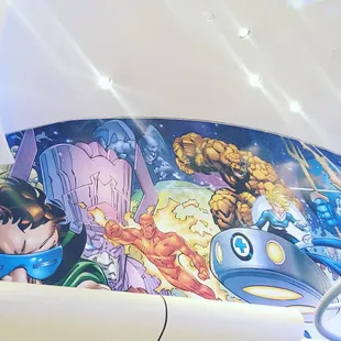 the interior of a restaurant with a mural on the wall