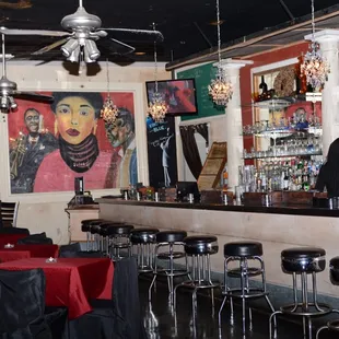 a bar with red tablecloths and black stools