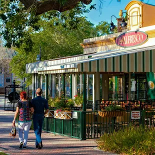 A couple walking by Café Alfresco's outdoor seating.