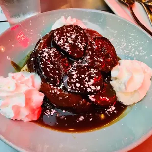 a plate of french toast with whipped cream and syrup