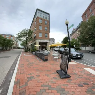 a brick sidewalk with tables and umbrellas