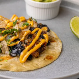 Baja Chicken Tacos: Grilled Chicken Tacos with Bacon, Black Beans, Melted Cheese, Spicy Mayo, Avocado &amp; Flour Tortilla.