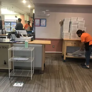 a man in orange shirt standing in front of a counter