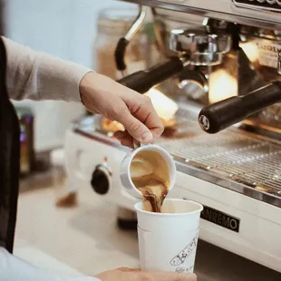 a person pouring coffee into a cup