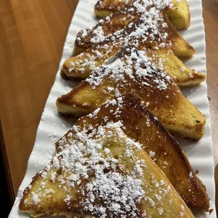 a plate of french toast with powdered sugar on top