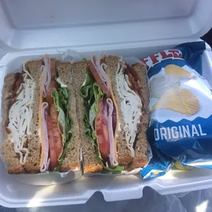 Club sandwich with chips and pickle on the side