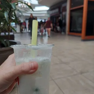 a hand holding a drink with a straw