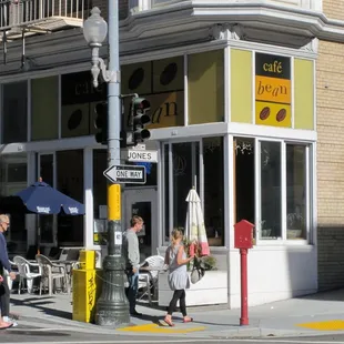 people walking on the sidewalk in front of a cafe