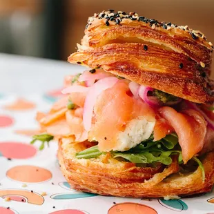 a croissant sandwich with salmon, lettuce, and tomato