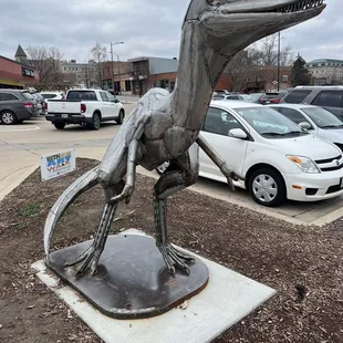 a dinosaur statue in a parking lot