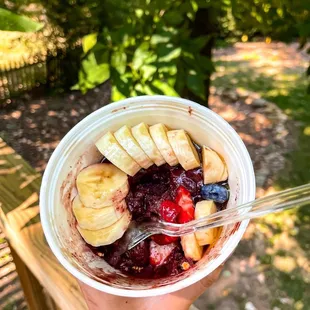 a hand holding a plastic cup filled with fruit