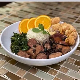Feijoada: popular dish from Brazil.  Pilaf rice, black beans with pork and sausage,collard greens, Yuka flour , pork skins and orange.