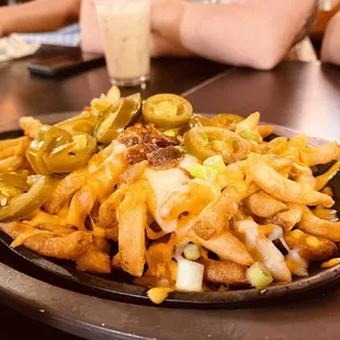 a plate of french fries with pickles and jalapenos