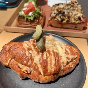 a croissant sandwich with a pickle on top