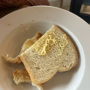 Not toasted toast with the butter not really spread on the toast.