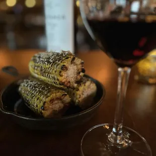 a plate of grilled corn and a glass of wine