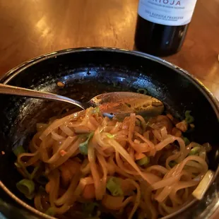 a bowl of noodles and a bottle of wine