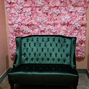 a green velvet couch in front of a pink wall