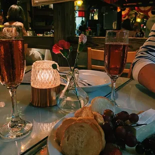 a plate of bread, grapes, and a glass of wine