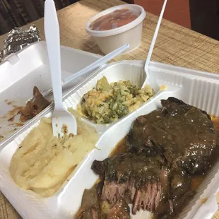 a tray of food with meat, potatoes, and gravy