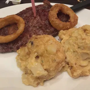 a steak, onion rings and mashed potatoes