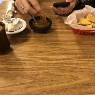a person using a cell phone and a bowl of chips and a cup of coffee